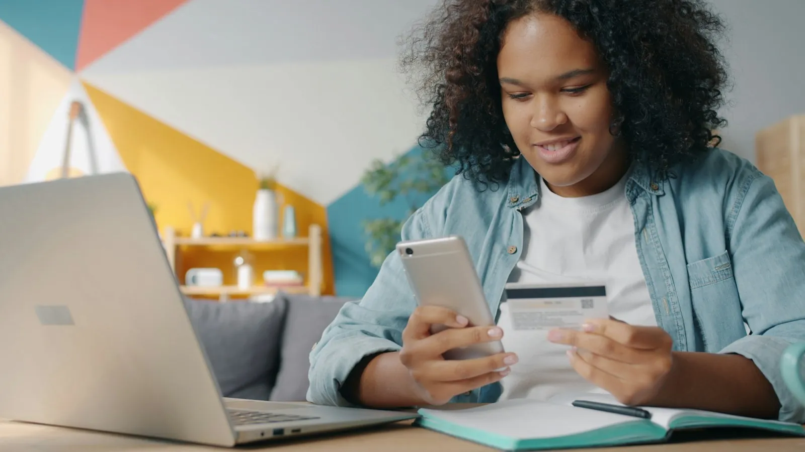 Adolescente usando telefone e cartão de crédito para compras online